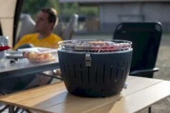 LotusGrill XL Hybrid Houtskoolbarbecue - Rood 22 LotusGrill XL Hybrid Houtskoolbarbecue - Rood -Online Camping Winkel lotusgrill in gebruik met toppy shirtje 2